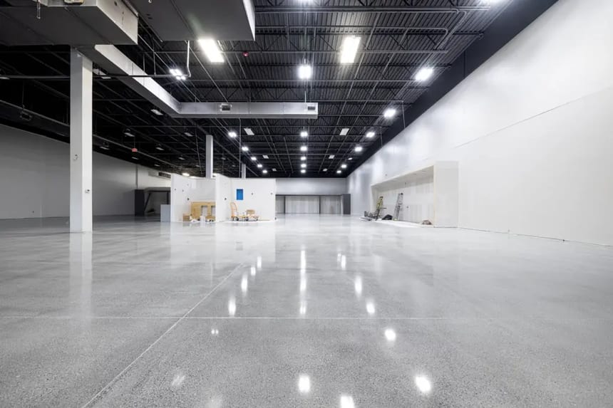 this image represents a high gloss polished concrete floor Highly polished concrete floor with mirror-like clarity in a large commercial interior, demonstrating low porosity and flatness
