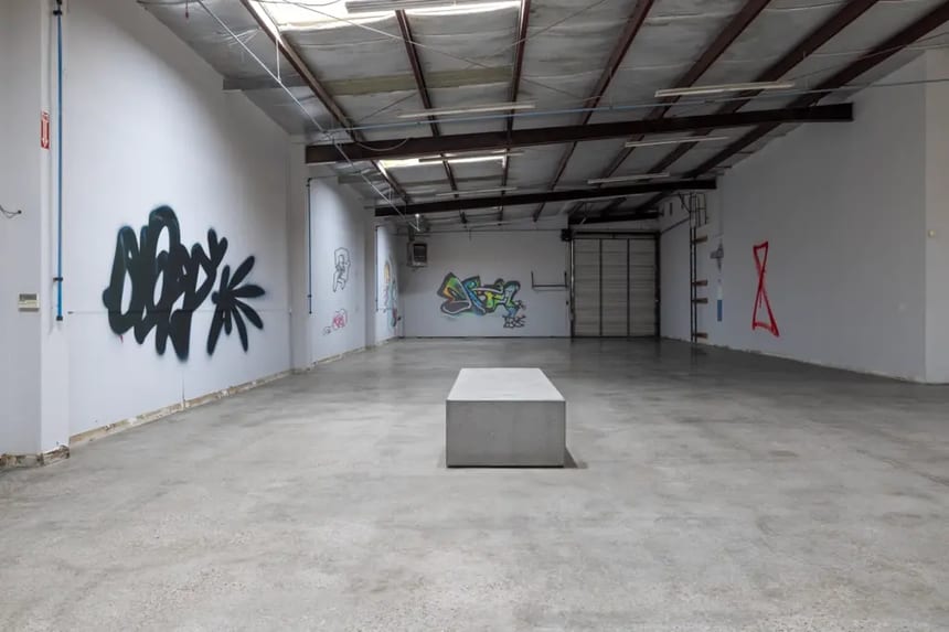 This image represents a low-gloss polished concrete floor Low-gloss polished concrete floor in a graffiti-covered warehouse, illustrating a Level 1 or 2 finish with minimal reflectivity