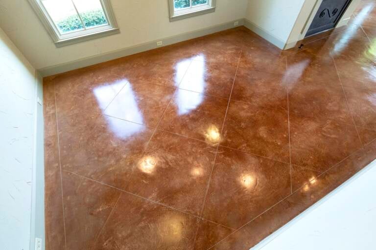 Reflective brown concrete floor with diagonal scored lines and window reflections
